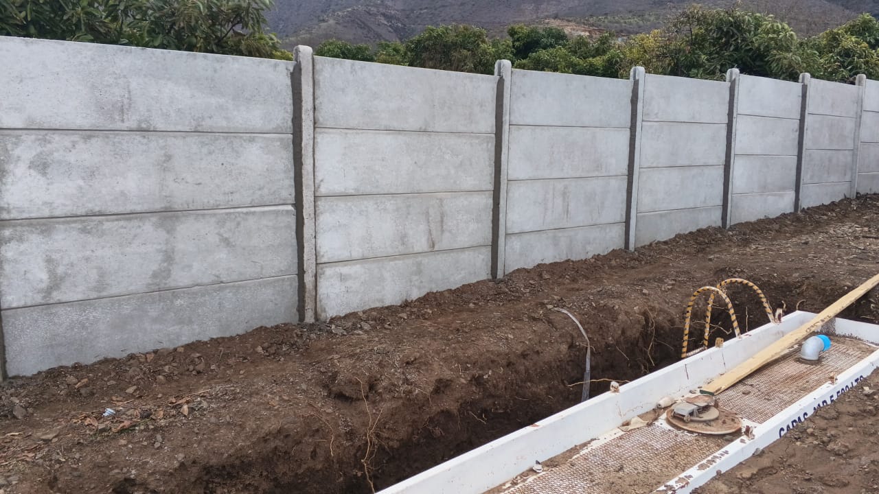 Instalación de cierre perimetral de hormigón junto a estructura en obra